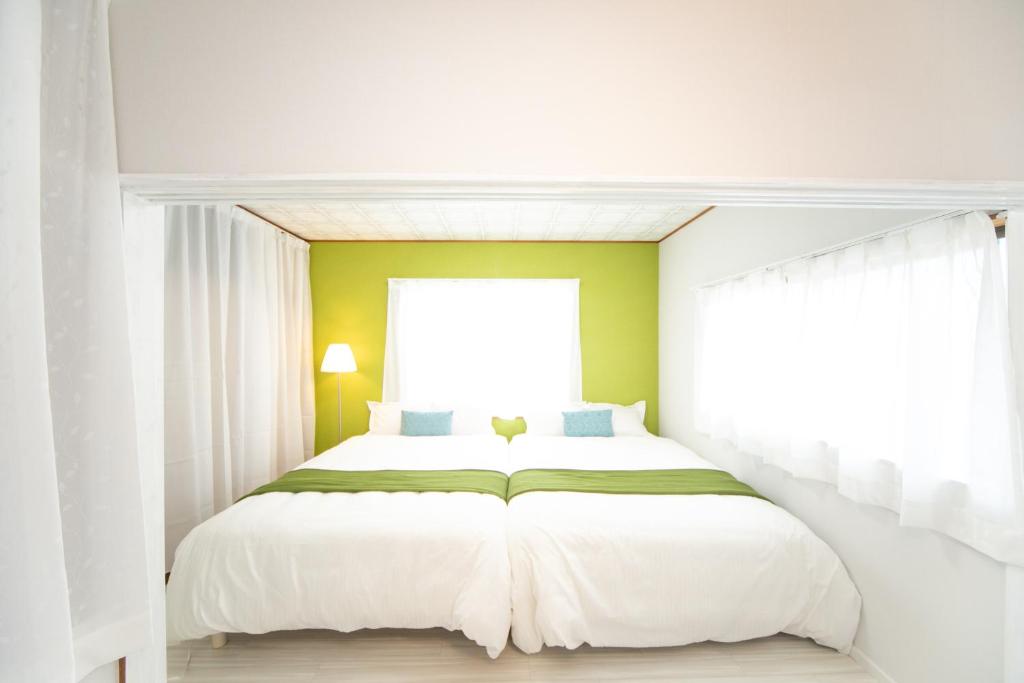 a bedroom with a large white bed with a window at Yokkaichi Higashihino Hotel in Yokkaichi