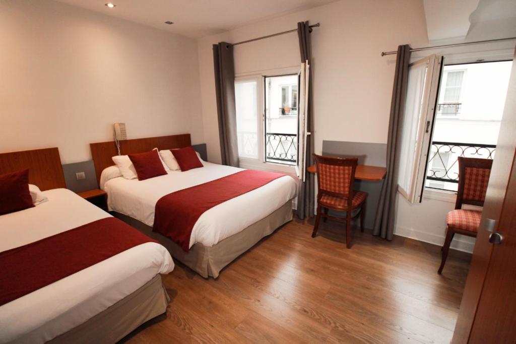 a hotel room with two beds and a table and chairs at Little Hôtel in Paris