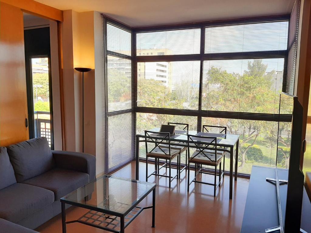 sala de estar con mesa, sillas y ventana grande en Barceló Cornellà en Cornellá de Llobregat