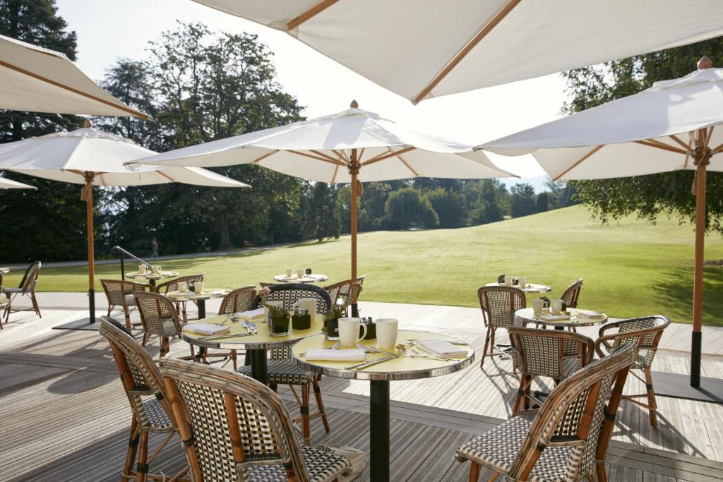 an outdoor patio with tables and chairs and umbrellas at Hôtel Royal in Évian-les-Bains