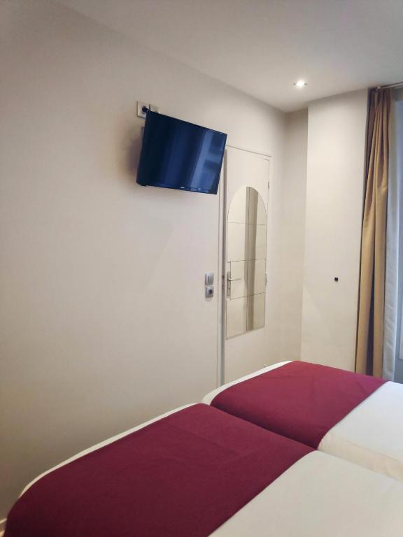 a bedroom with a bed with a tv on the wall at Little Hôtel in Paris