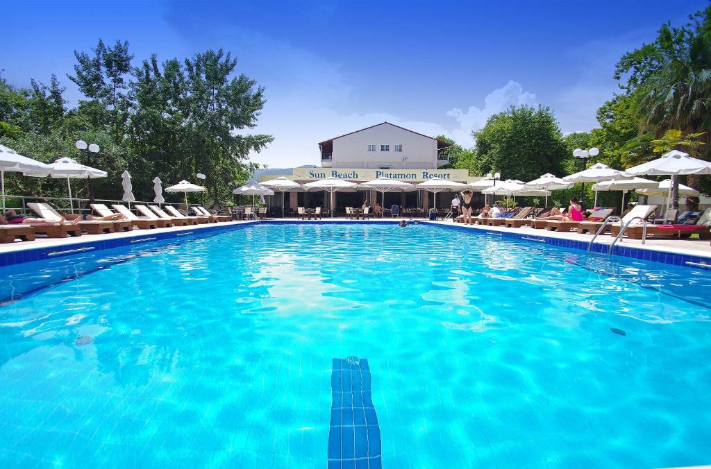 a large blue swimming pool with chairs and umbrellas at Sun Beach Hotel in Platamonas