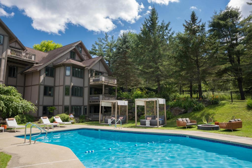 a house with a swimming pool in front of a house at Field Guide Lodge in Stowe