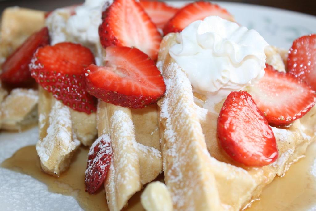 a waffle with strawberries and whipped cream on a plate at The Harbour House in Charlottetown