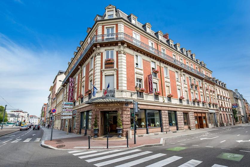 een groot gebouw op de hoek van een straat bij Hotel Bristol in Mulhouse