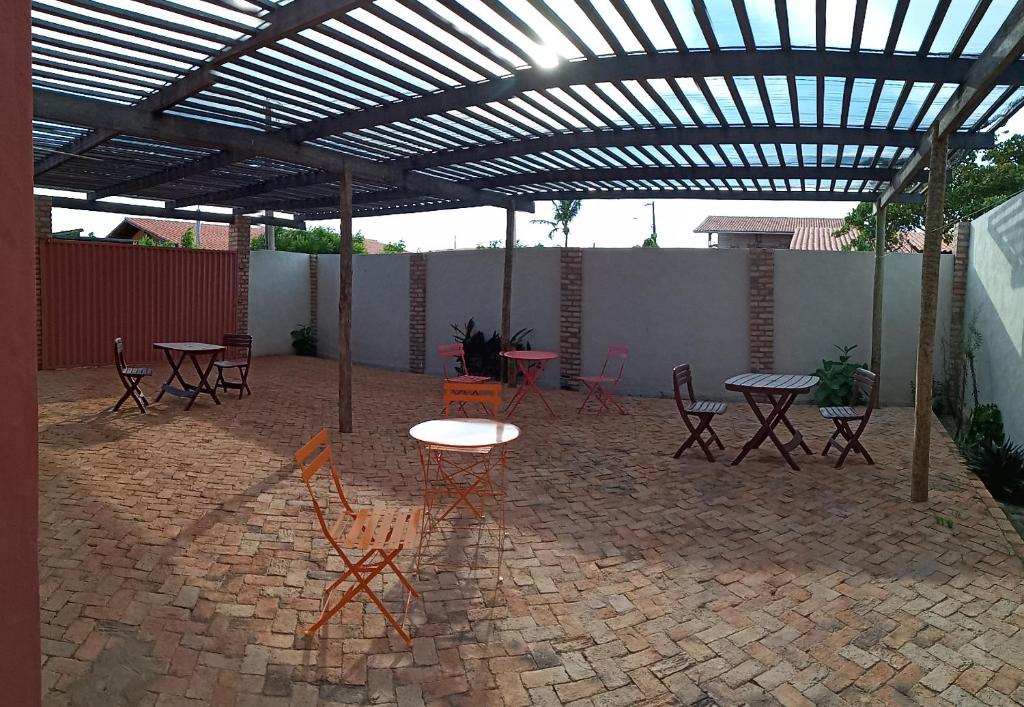 un patio con mesas y sillas bajo una pérgola en LA MAISON OLIVER SPEEDS, en São Miguel do Gostoso