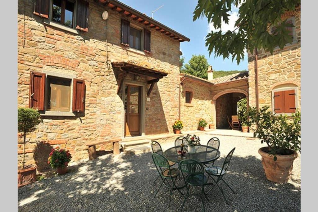 a patio with a table and chairs in front of a building at Tuscan Charme of Cottage Roccaio Countryside Cortona in Castiglion Fiorentino