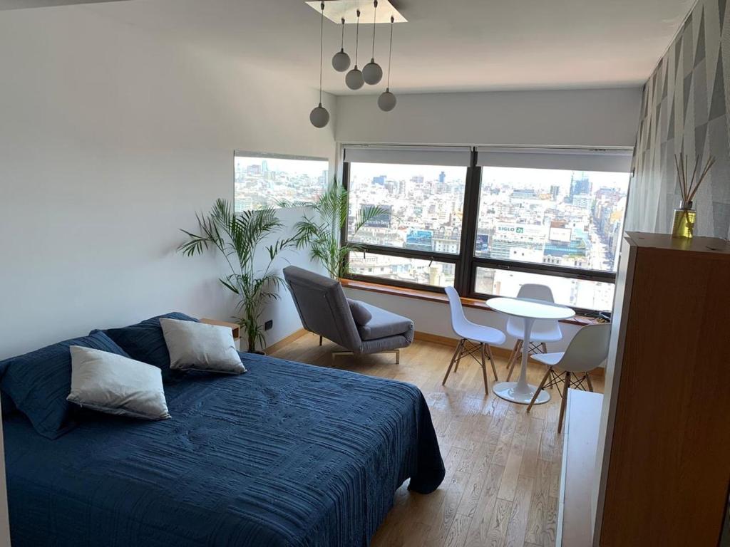 1 dormitorio con 1 cama azul, mesa y sillas en BUENOS AIRES BEST SKYSCRAPER en Buenos Aires