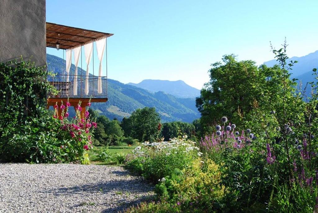 un giardino fiorito e un edificio con montagne sullo sfondo di l'Ancienne Ecole du Villard a Saint-Pierre-dʼEntremont