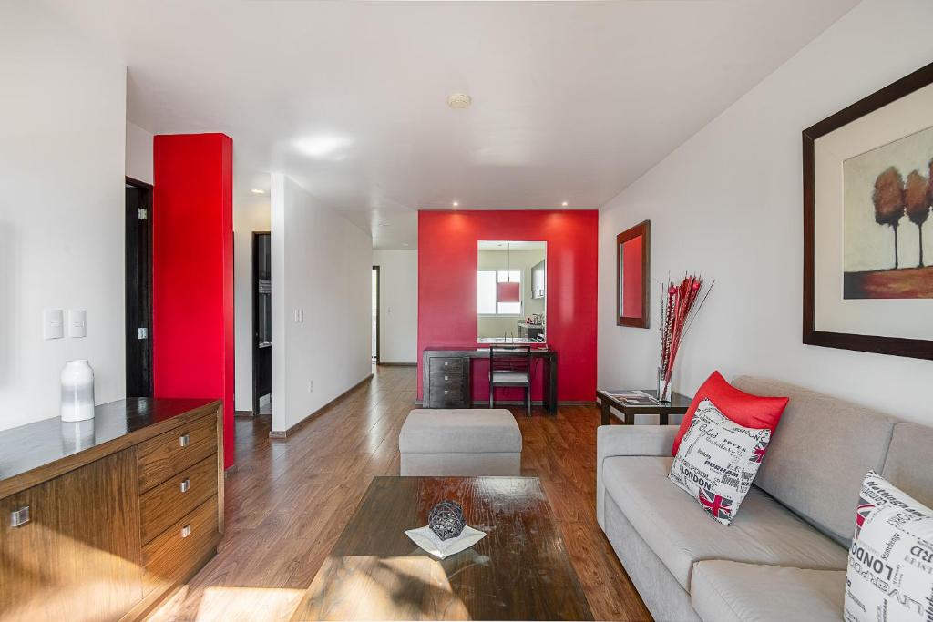 Suites Copérnico Polanco Anzures في مدينة ميكسيكو: غرفة معيشة مع أريكة وجدار احمر