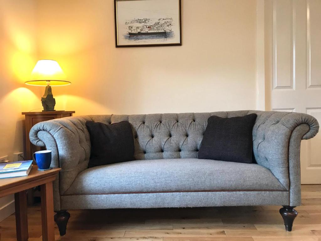 um sofá numa sala de estar com uma mesa e um candeeiro em 10 Berisay Place em Stornoway