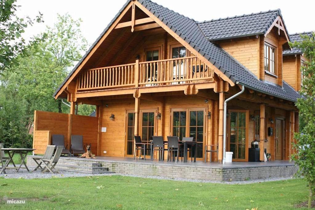 a large wooden house with a deck and patio at Houten Villa Dirk in Den Ham