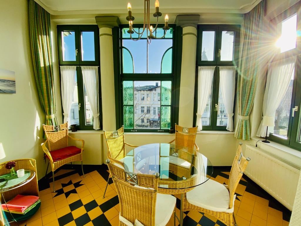 Zimmer mit einem Glastisch, Stühlen und Fenstern in der Unterkunft Dreiraumwohnungen - Villa Donatus in Ahlbeck