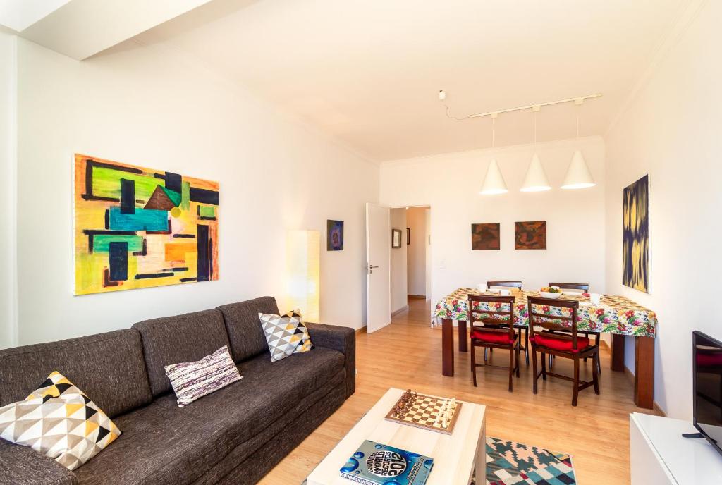 a living room with a couch and a dining room at White Apartment - T2 near Beach in São João do Estoril