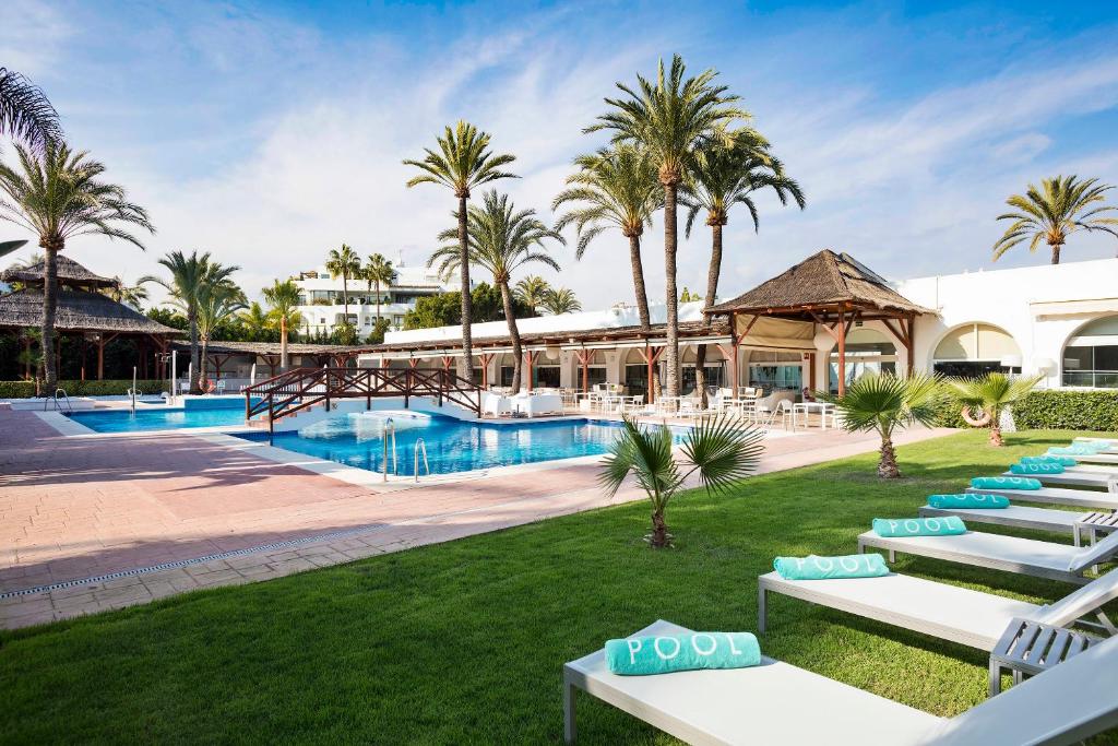 a beach area with a pool, chairs, and lawn chairs at Melia Marbella Banús in Marbella