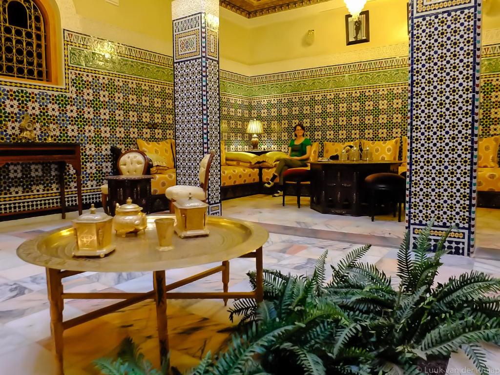 a room with a table and a woman in the background at Dar Al Madina Al Kadima in Fez