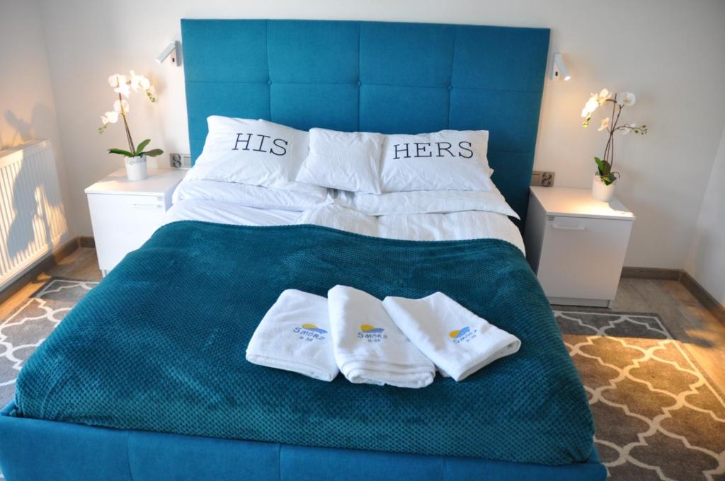 Una cama azul con dos pares de toallas. en Apartament LAZUROWY Pięć Mórz - Sianożęty en Sianozety