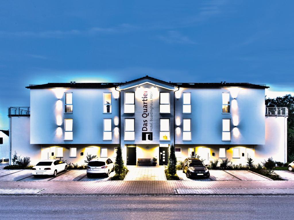 un grand bâtiment avec des voitures garées dans un parking dans l'établissement Das Quartier, à Karlskron