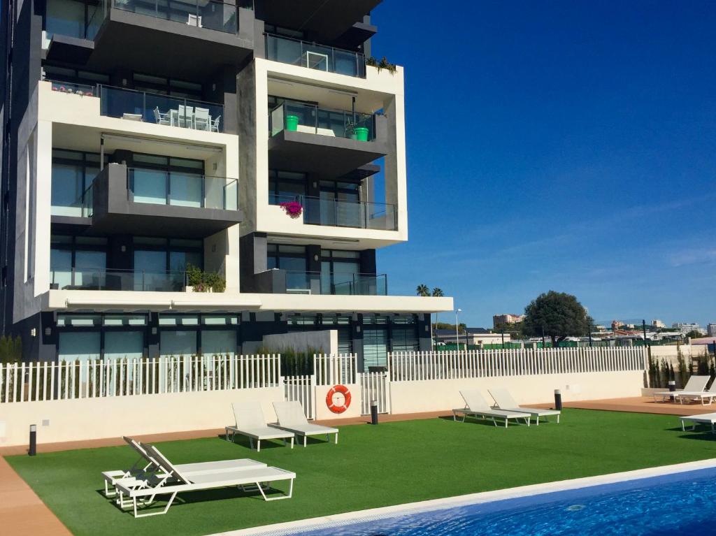 a building with a pool and lounge chairs in front of it at Sea View Apartment Arenal Beach Calpe in Calpe