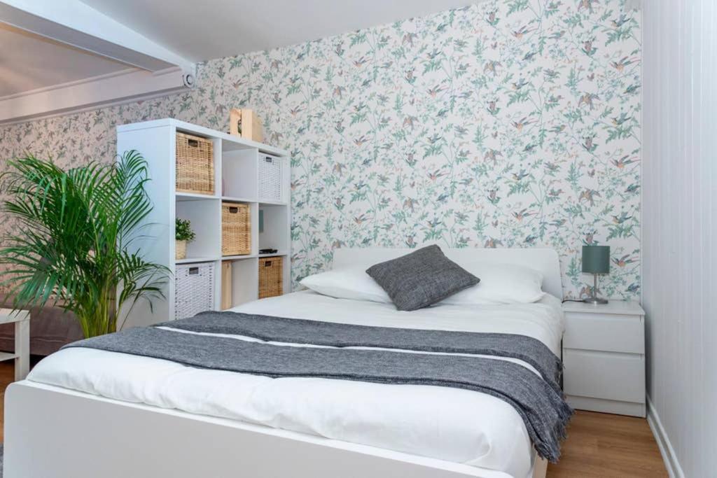 1 Schlafzimmer mit einem weißen Bett und Blumentapeten in der Unterkunft Appartement au calme + parking in Caen