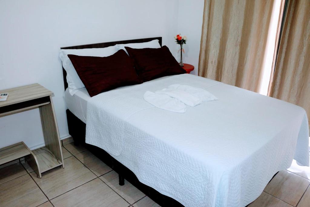 a bedroom with a large white bed with a window at Hotel Edinik in Cafelândia