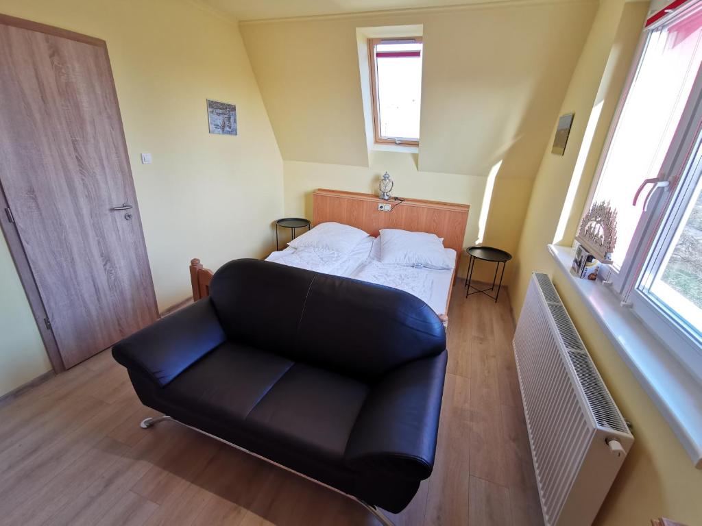 Cette chambre comprend un lit et un canapé en cuir noir. dans l'établissement Kérész Panzió, à Mártély
