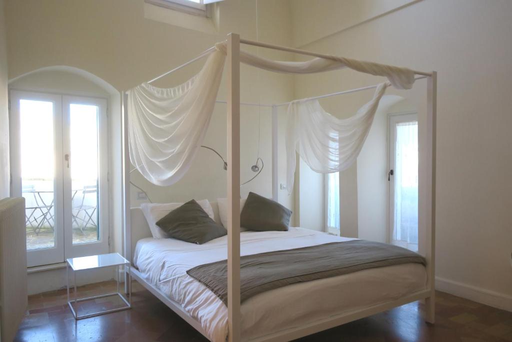 a bedroom with a four poster bed with windows at La Corte Dei Cavalieri in Matera