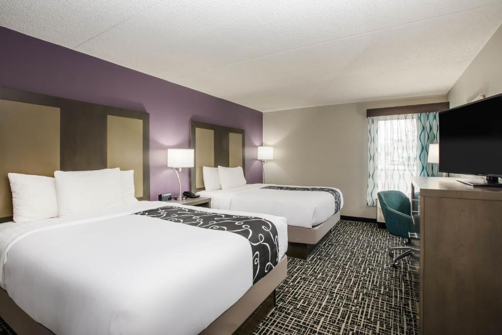 um quarto de hotel com duas camas e uma televisão de ecrã plano em La Quinta Inn by Wyndham Davenport & Conference Center em Davenport