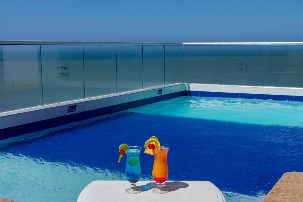 two glasses sitting on a table in a swimming pool at Hotel Aixo Suites By GEH Suites in Cartagena de Indias