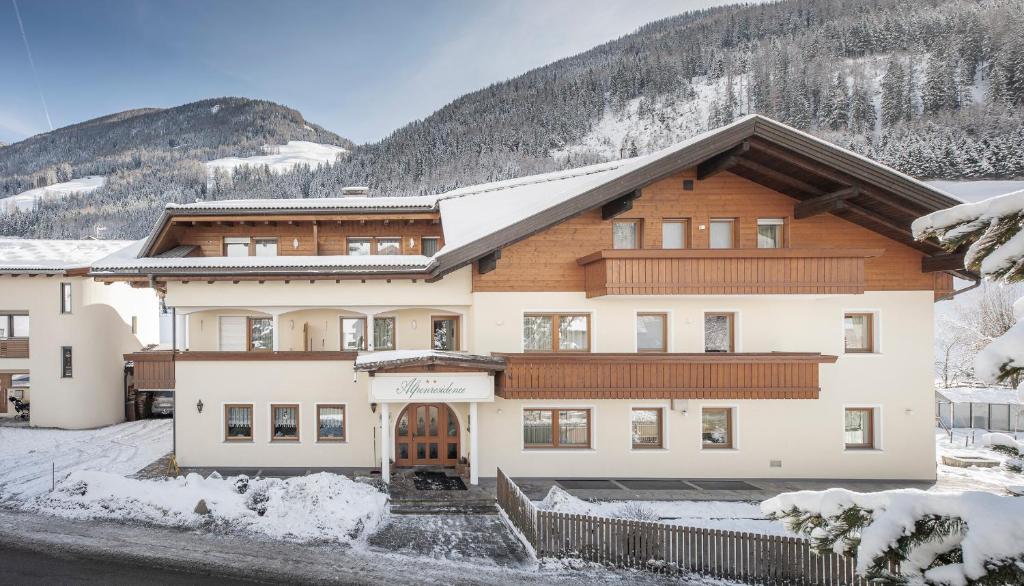 un gran edificio con montañas cubiertas de nieve en el fondo en Garni Appartement Alpenresidence en Cadipietra