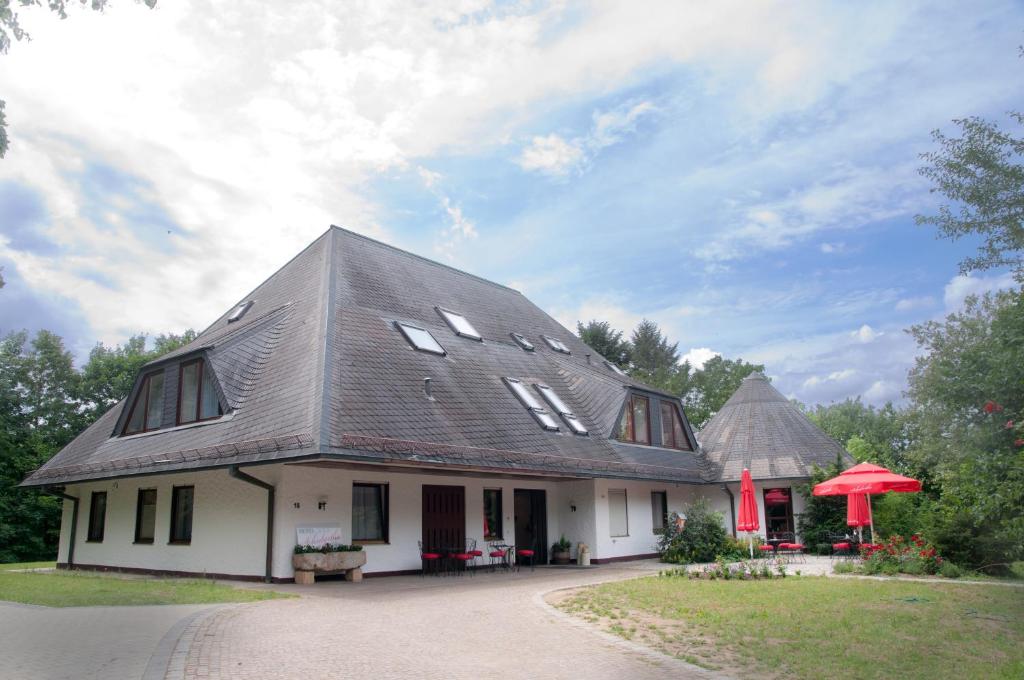 Hotel Schuberths am Schloss في Buttenheim: منزل بسقف مقامر مع مظلة حمراء