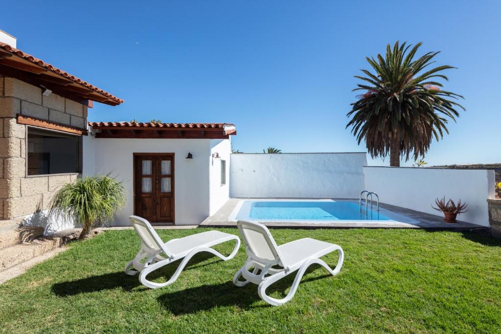 a yard with two lounge chairs and a swimming pool at El Sitio de la Casa in Arico el Nuevo