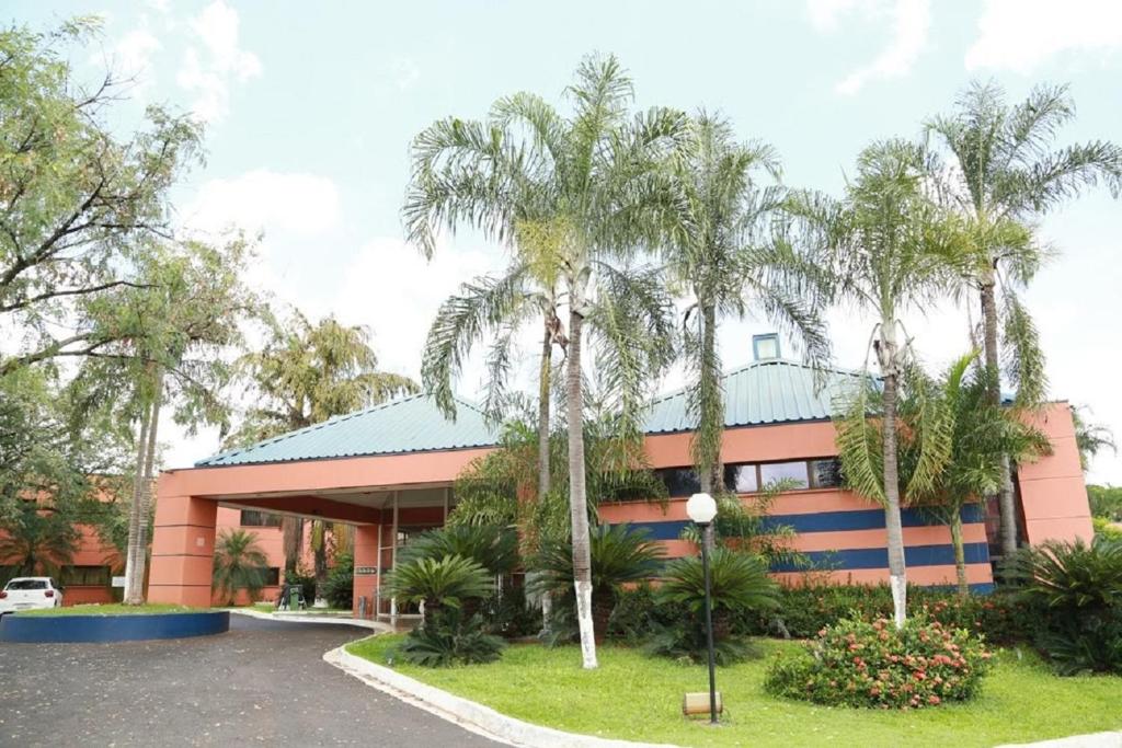 a building with palm trees in front of it at Hotel Golden Park Ribeirão Preto in Ribeirão Preto