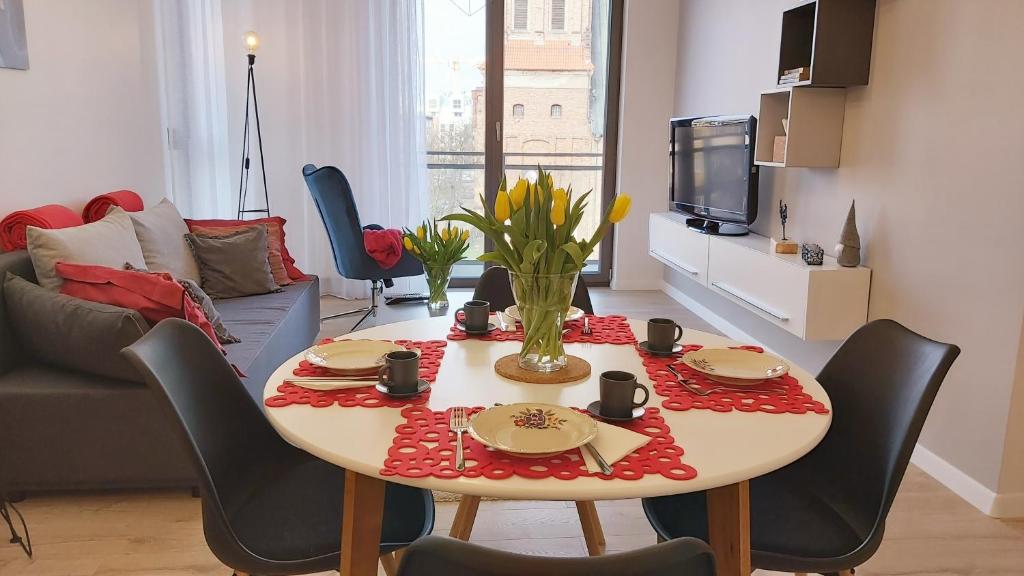 a living room with a table with chairs and a couch at Central Apartments Ogrody 1 & Parking in Gdańsk