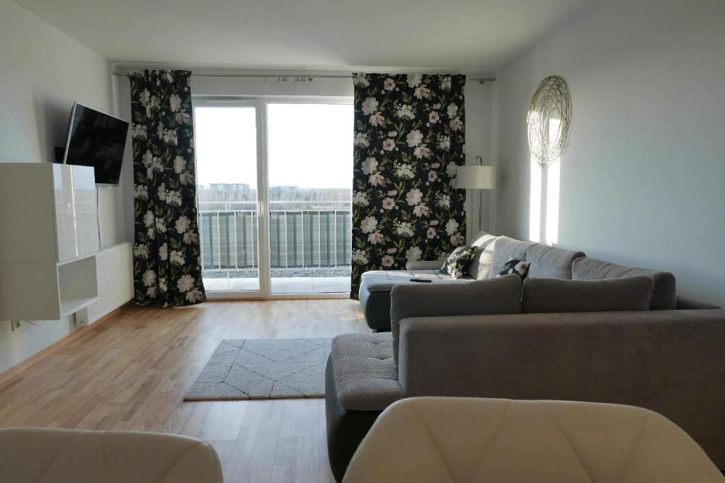 a living room with a couch and a large window at Apartament Soft 16 in Biała Podlaska