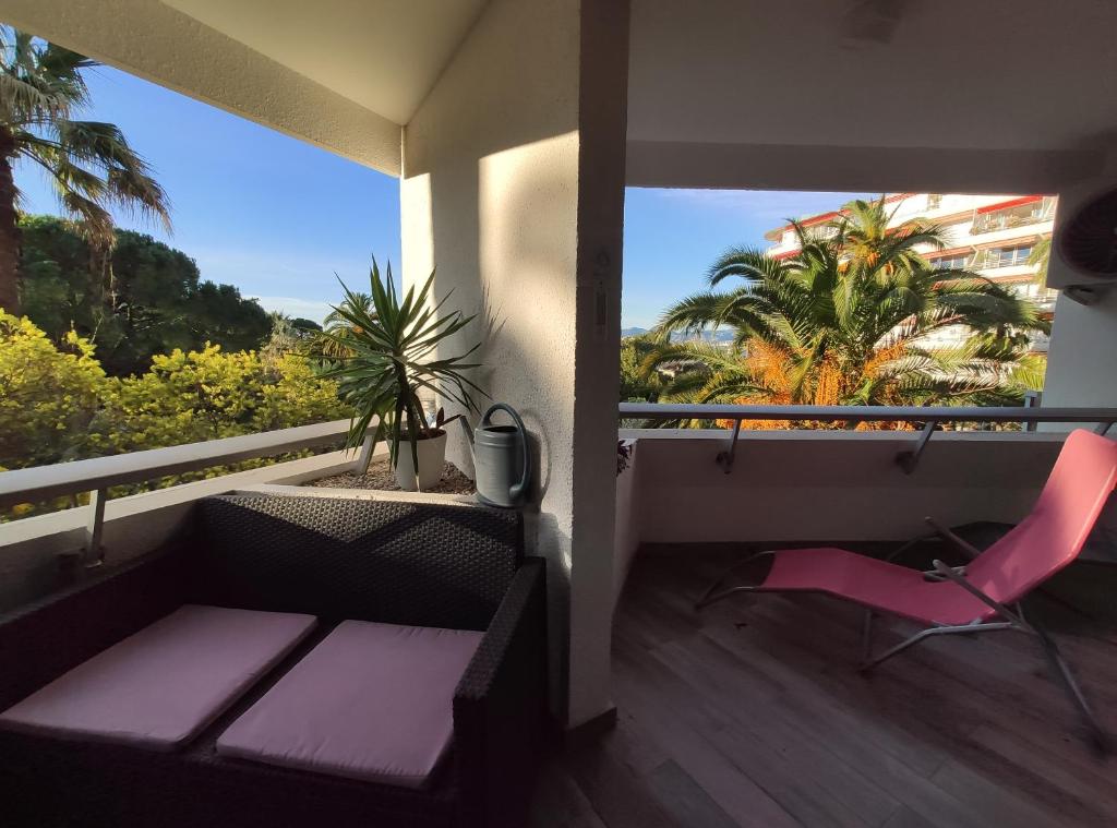 a balcony with a pink chair and a view of palm trees at Très beau T2 dans parc montfleury ,proche centre ,au calme 44 bd Montfleury in Cannes