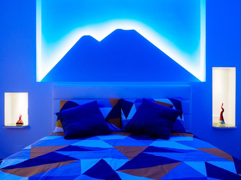 niebieska sypialnia z łóżkiem z górskim malowidłem w obiekcie Plebiscito Home Holidays w mieście Napoli