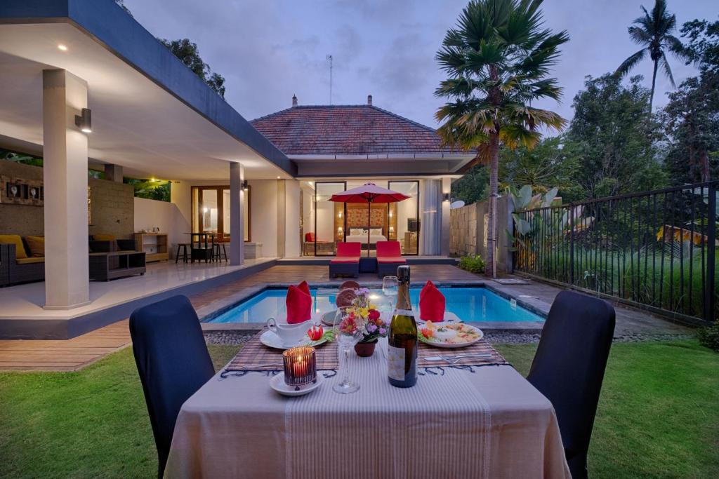 a dining table in a backyard with a pool at Nadira Bali Villa in Munduk