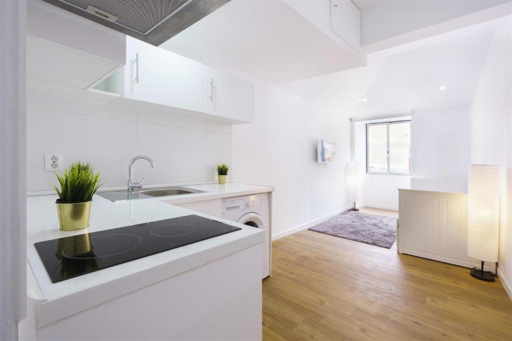 a white kitchen with a sink and a stove at Central Lisbon Studio in Lisbon