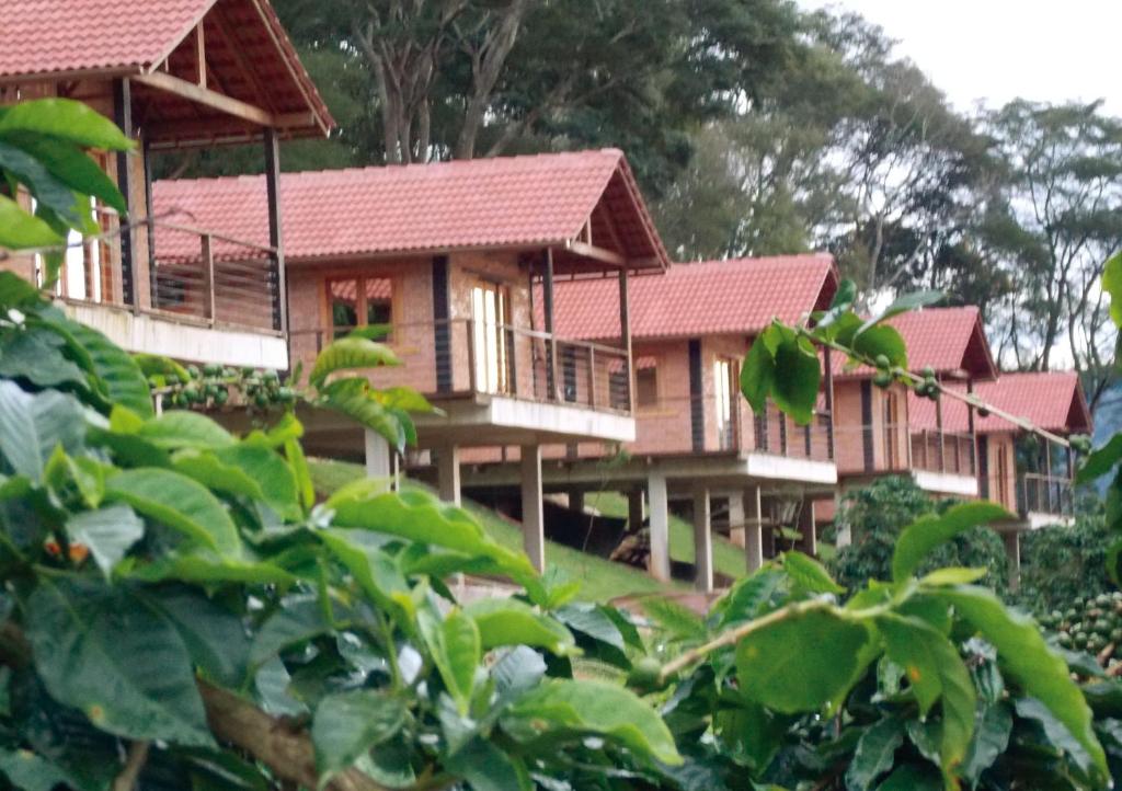 um edifício de resort com telhados vermelhos e árvores em Pousada Café da Mata em Caparaó Velho