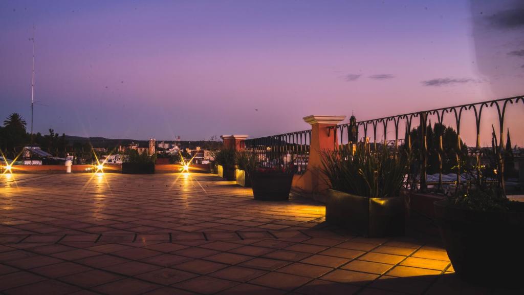 eine Terrasse mit Topfpflanzen und einem Zaun in der Nacht in der Unterkunft Hotel del Capitán de Puebla in Puebla