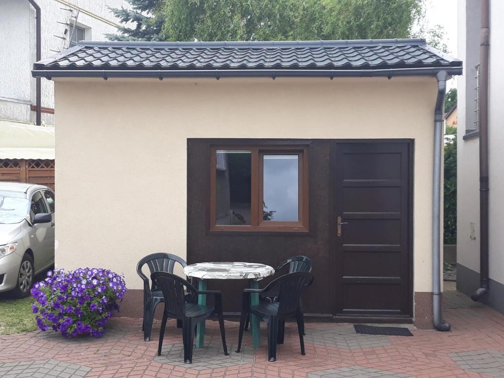 een patio met een tafel en stoelen voor een schuur bij Domek u Hermana in Mrzeżyno