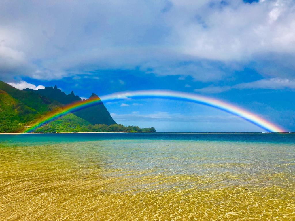 a rainbow over a body of water at Haena Kai home in Haena