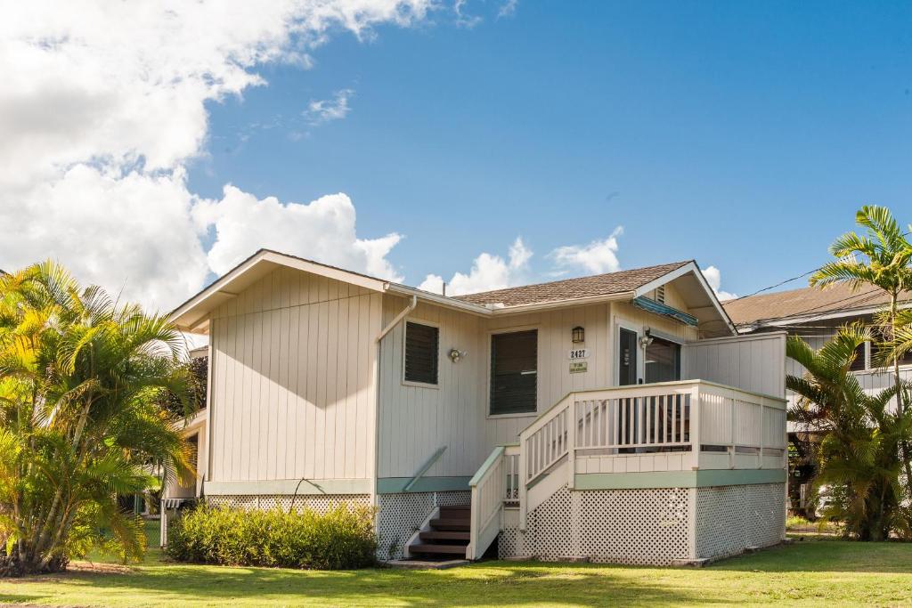 a house with a balcony and palm trees at Malu Kauai, a Beautiful Kauai Cottage 1 Mile from Kalapaki Beach home in Lihue