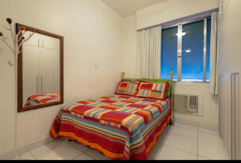 um quarto com uma cama, um espelho e uma janela em Apartamento Posto 6 no Rio de Janeiro