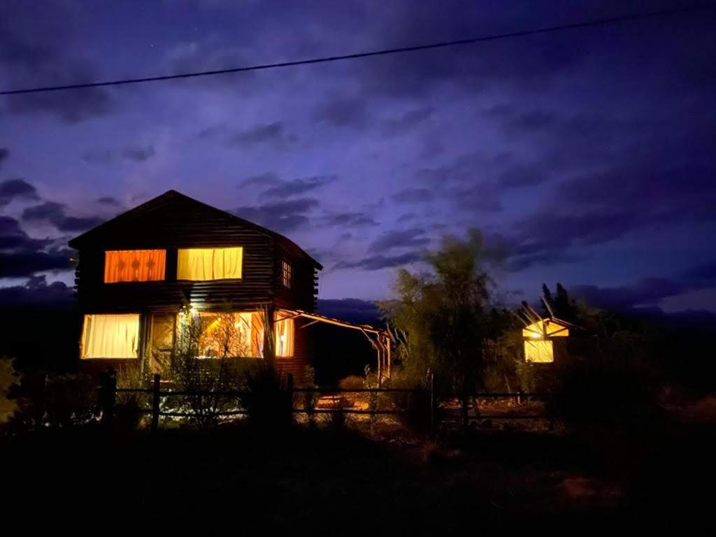 una casa iluminada por la noche con luces encendidas en Cabañas LUNA en Uspallata