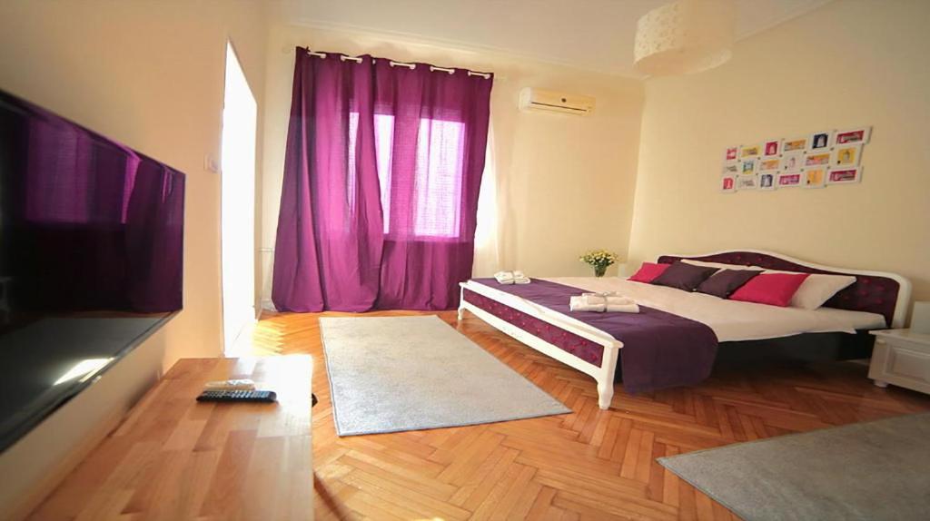 Una sala de estar con una cama y un televisor. en Apartment Central, en Belgrado