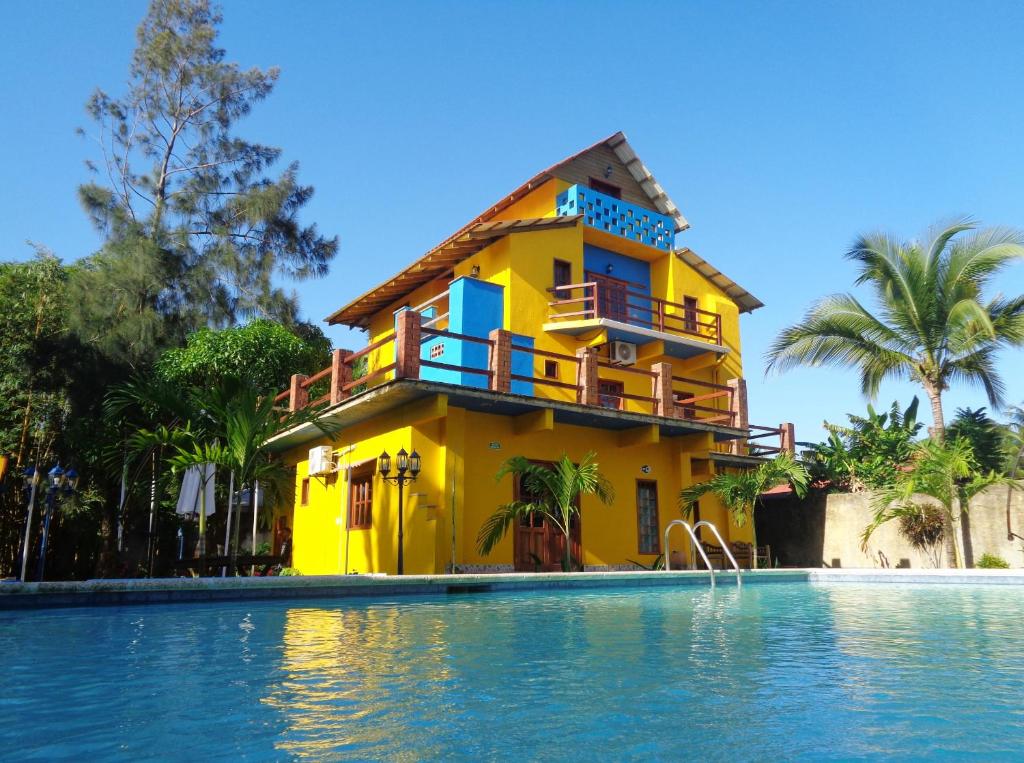 una casa amarilla junto a una piscina en Livingston Resort Hotel, en Lívingston