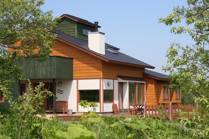 a large wooden house with a porch and chairs at ポロト案内舎 in Hamanaka