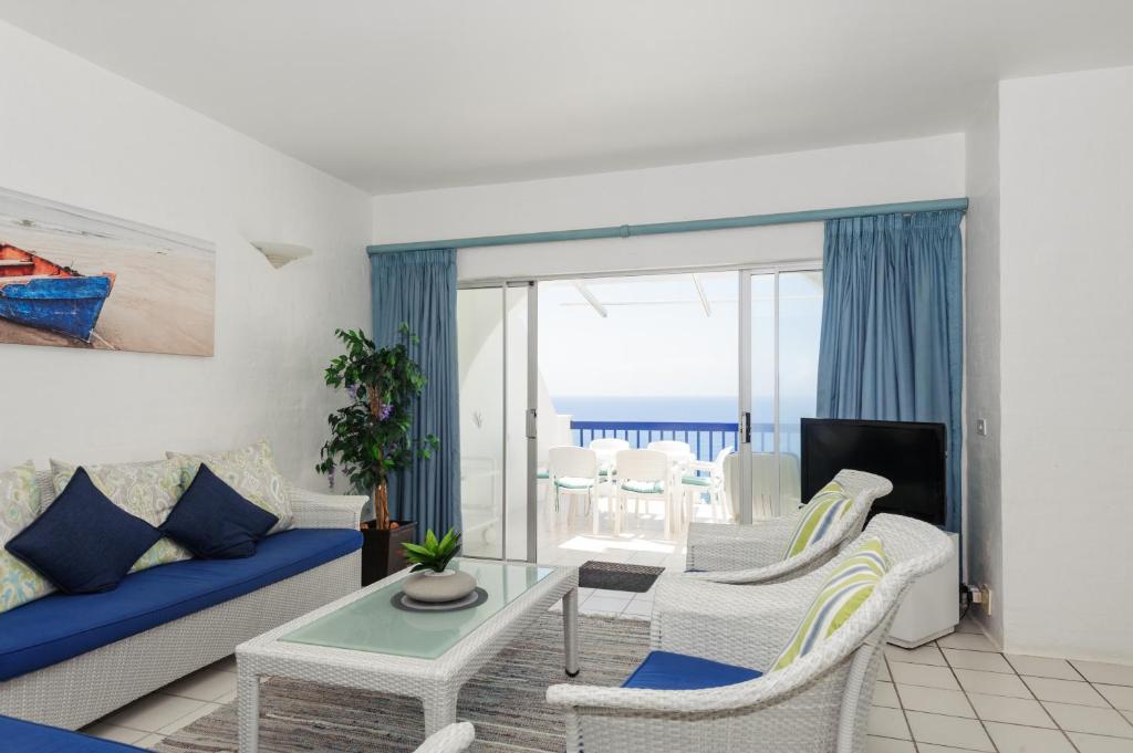 ein Wohnzimmer mit einem Sofa, einem Tisch und Stühlen in der Unterkunft Santorini Akrotiri 30 - Family only in Ballito